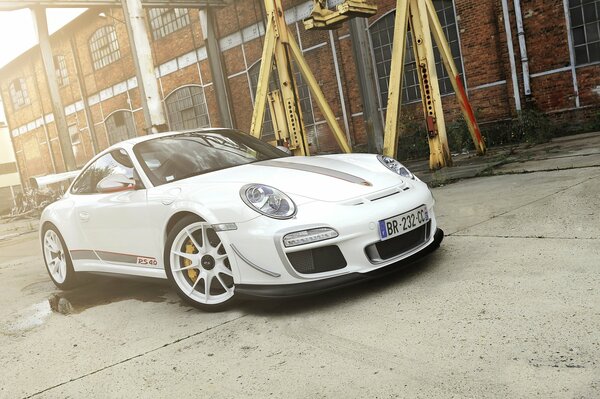 Porsche blanco de pie en el fondo de una fábrica de ladrillos