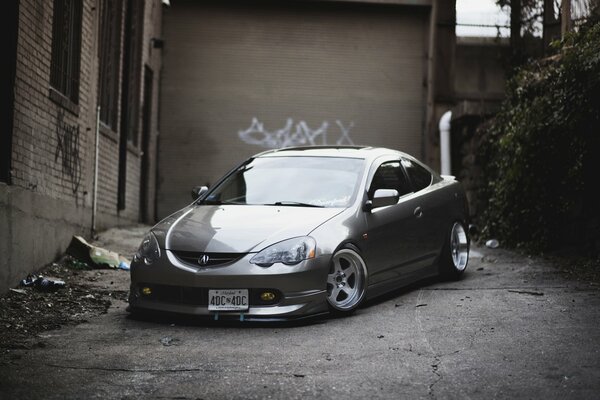 Silver car Akura with a low-slung body on the background of a wall with graffiti