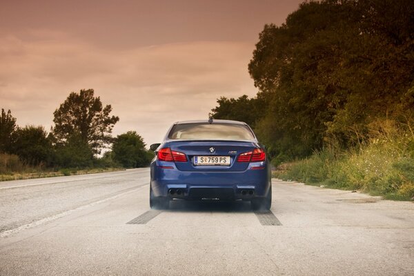 Синий bmw по дороге с небесными облаками