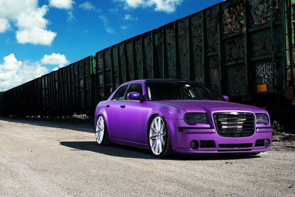Chrysler 300C tuning violet à côté des voitures de chemin de fer
