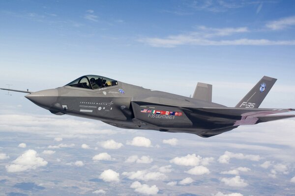 A grey fighter jet is flying above the clouds