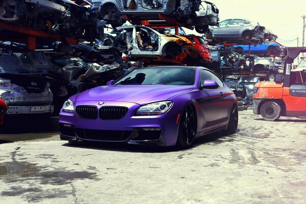 BMW morado sobrio en Llantas de aleación negras se encuentra en el sitio de reciclaje de automóviles