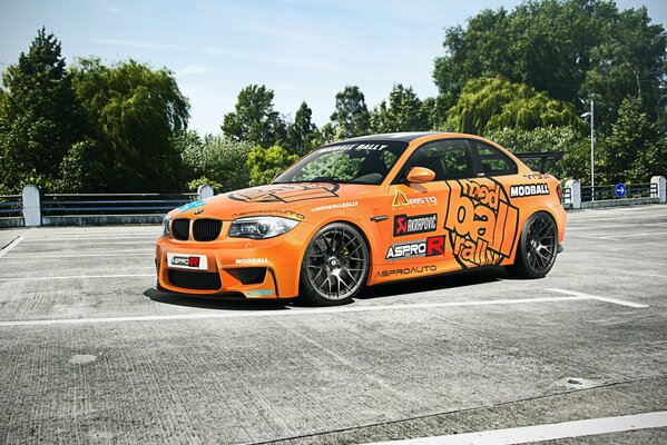 Orange car on a background of green trees