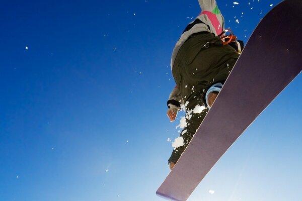Cloudless blue sky with a snowboarder close-up