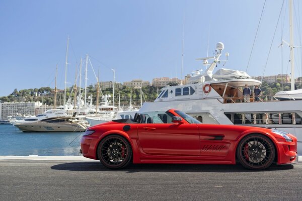 Czerwony mercedes-benz nad oceanem otoczony jachtami