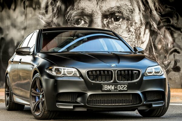 Чёрная BMW m5 на фоне картины