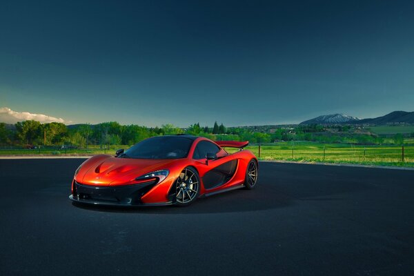 Mclaren rossa su uno sfondo di paesaggio verde