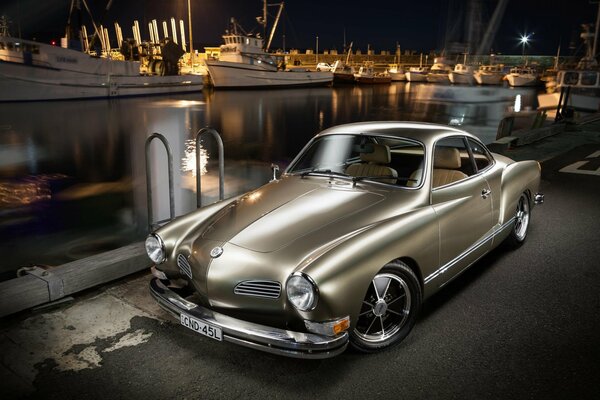 Silver Volkswagen 1973 on the embankment by the river with standing yachts