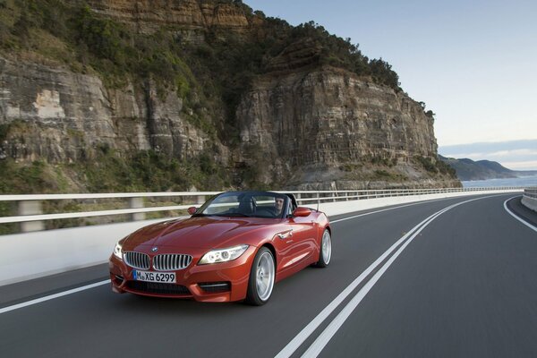 Ein rotes Cabrio fährt auf der Straße inmitten einer malerischen Landschaft