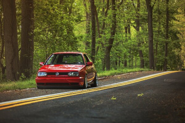 Volkswagen rouge Monte sur la route dans la forêt