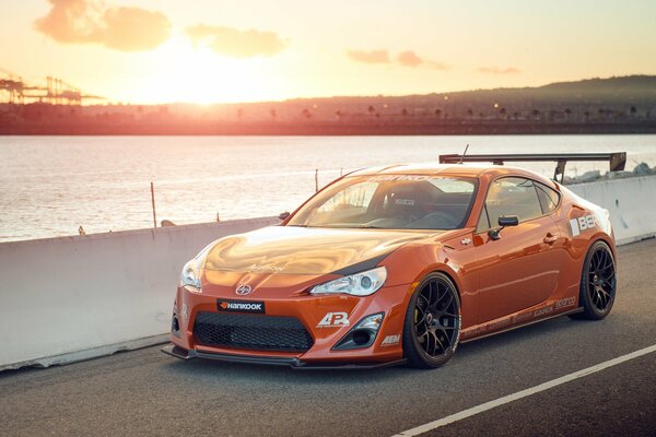 Auto sintonizzata arancione di Toyota skion al tramonto