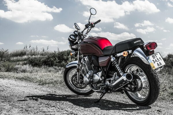 The Honda CB1100 motorcycle stands on a dirt road