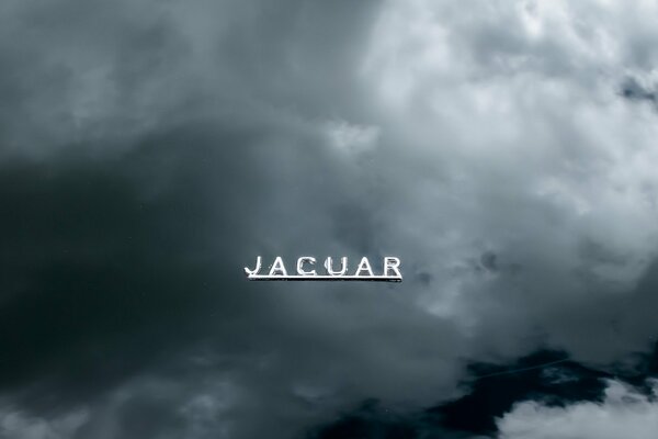 Metaliczny napis Jaguara na tle chmur