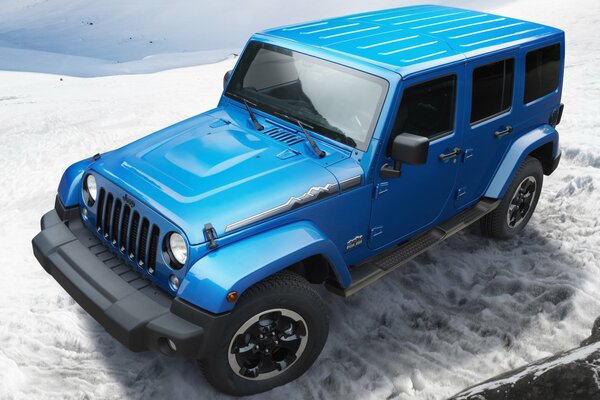 Blauer Wrangler-Jeep in den schneebedeckten Bergen