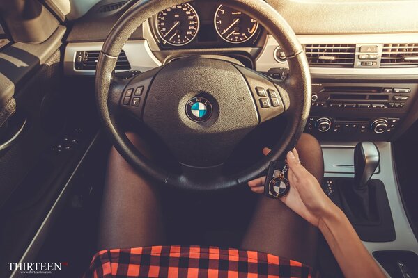 A girl with keys at the wheel of a bmw salon