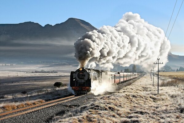 An old passenger locomotive on the background of a mountain with fog