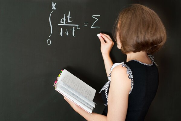 A teacher standing at the blackboard with a textbook