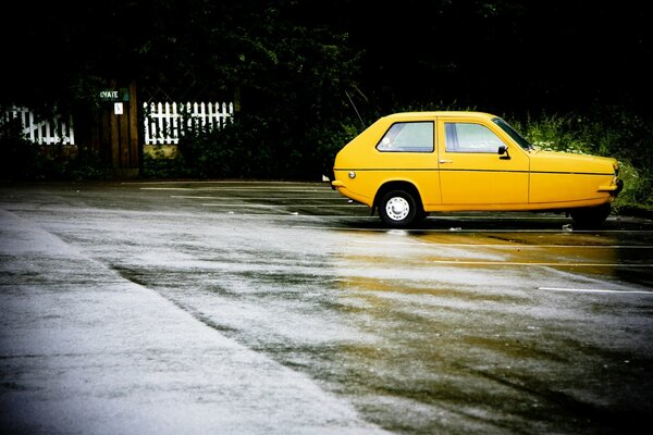 Auto amarillo en asfalto mojado