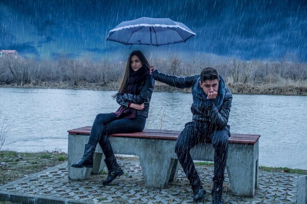 Fille et mec assis sur un banc sous la pluie