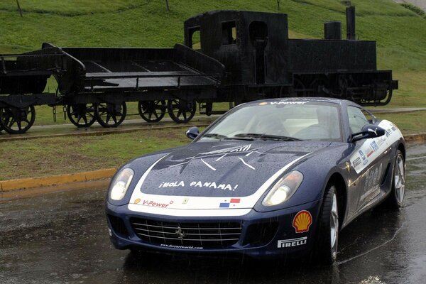 A sports car on the background of a steam locomotive from the last century