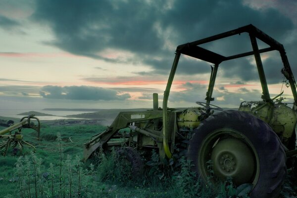 Abandoned broken tractor on the grass in the field