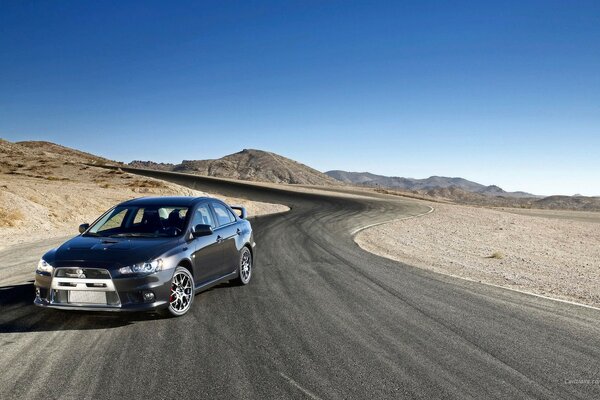 Mitsubishi coche negro en la carretera del desierto