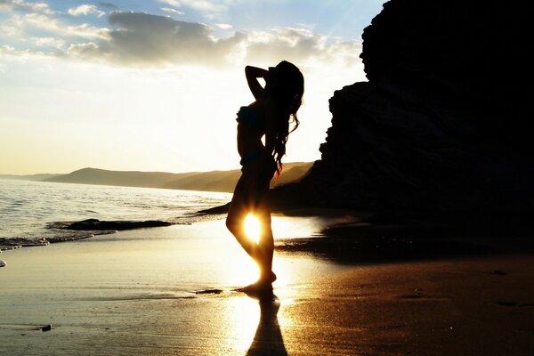 A model poses on the ocean , at sunset