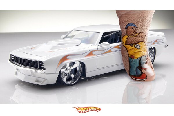 A toy car and an art drawing of a man on a finger