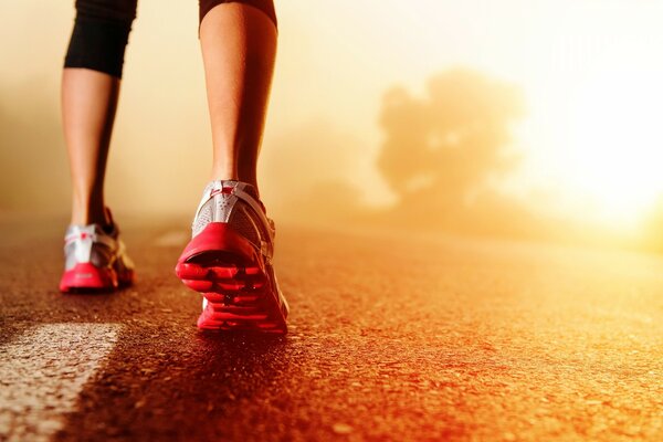 Women s feet in sneakers on the asphalt