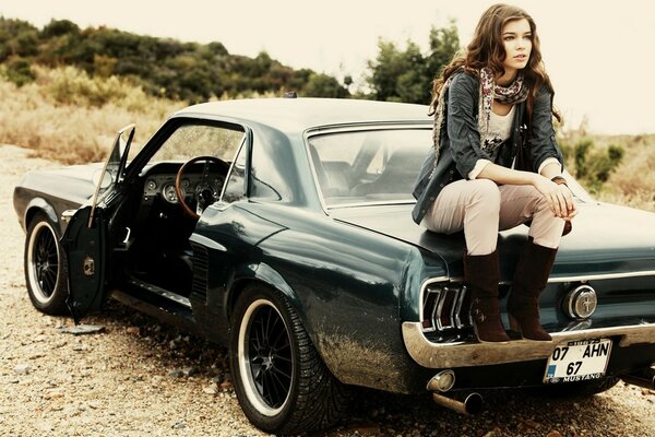 Fille assise sur une Mustang grise