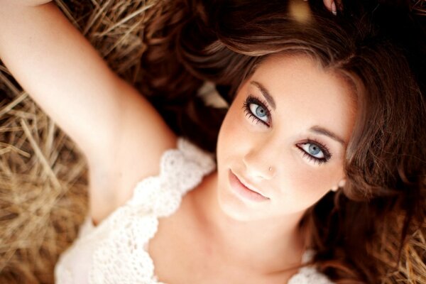 A girl with brown hair on a haystack