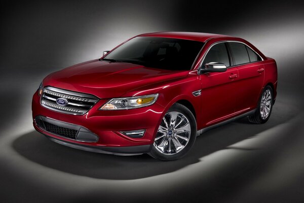 A luxury car in red on a gray background. Red sparkling Ford Taurus