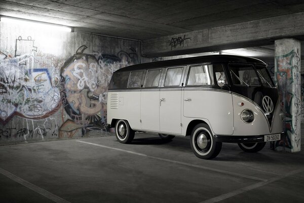 A white Volkswagen stands in the garage against the background of graffiti