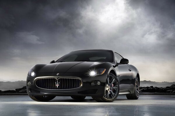 Negro Maserati granturismo con los faros encendidos