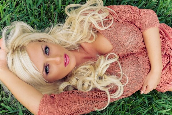 Piękna blondynka leży na trawie