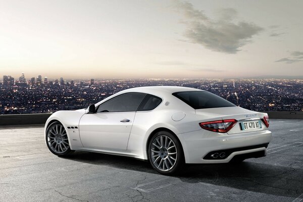 Maserati grandturismo bianco con vista sulla città