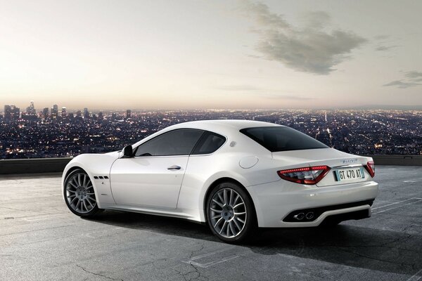Maserati grandturismo w kolorze białym z widokiem na miasto