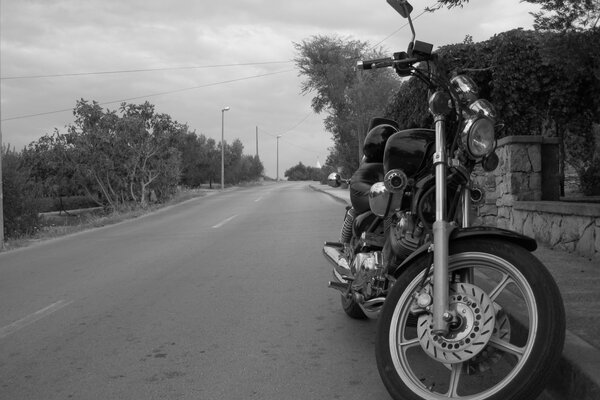 Motorrad auf dem Hintergrund einer verlassenen Wanderstraße in den Farben schwarz und weiß