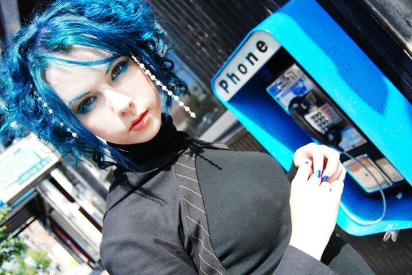 Ragazza con i capelli blu vicino al telefono