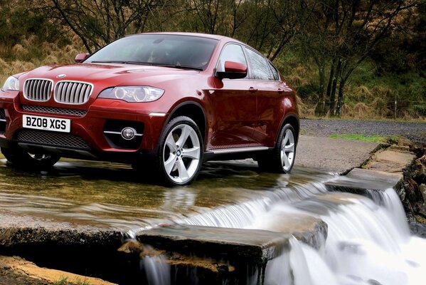 Bmw rouge dans la nature devant une cascade