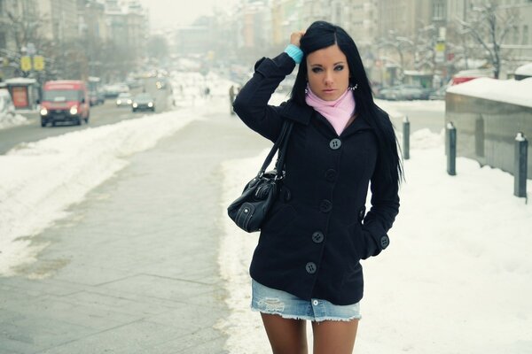 Ragazza in piedi nel mezzo di una strada innevata