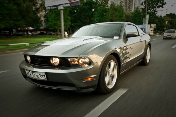 Na torze srebrny samochód Mustang z płonącymi reflektorami