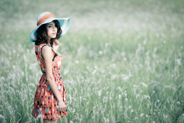 A girl in a hat in the green grass