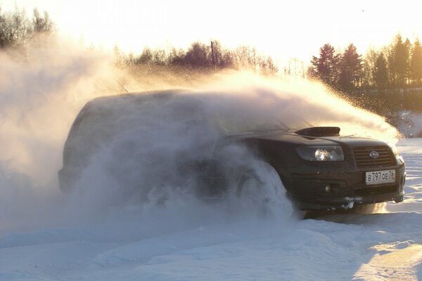 On a snowy highway, a black Subaru, struggling through the snow