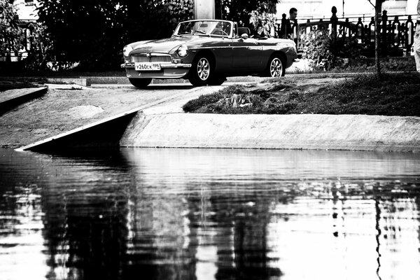 Czarno-białe zdjęcie z wizerunkiem samochodu nad wodą