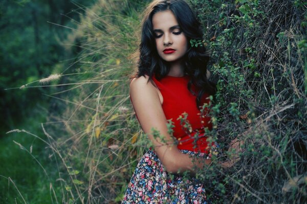 Morena en camiseta roja por el árbol