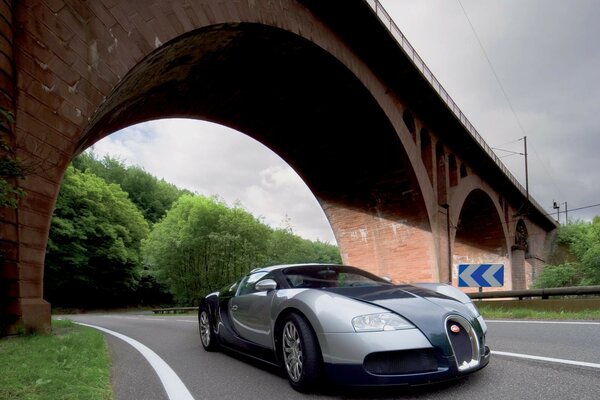 Coche Bugatti parado en la carretera debajo del puente