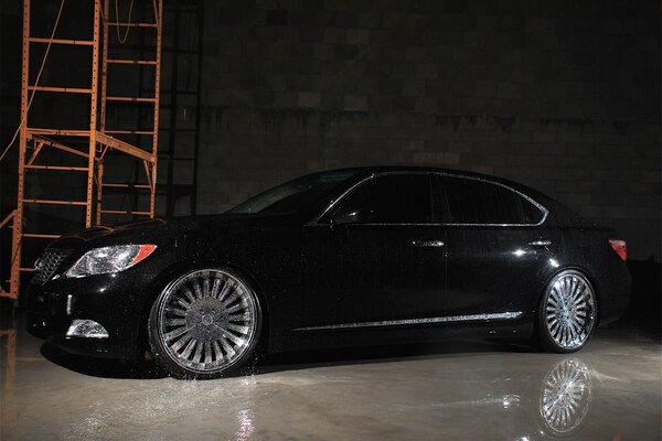 Lexus negro cubierto con agua en el hangar