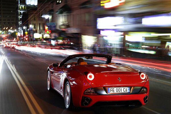 Ein roter Ferrari rast nachts mit hoher Geschwindigkeit über die Straße