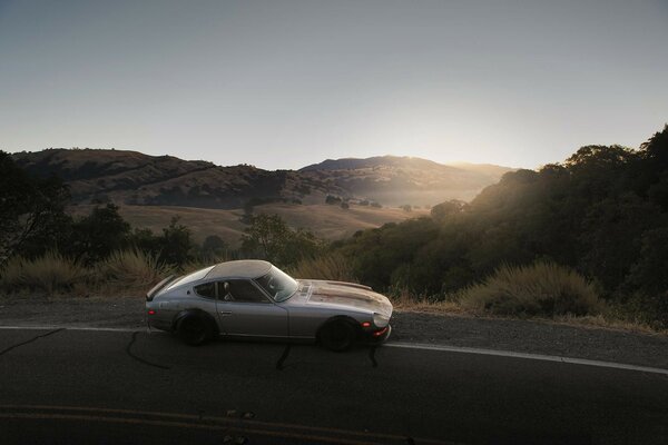 A car standing on the side of the road against the sunset